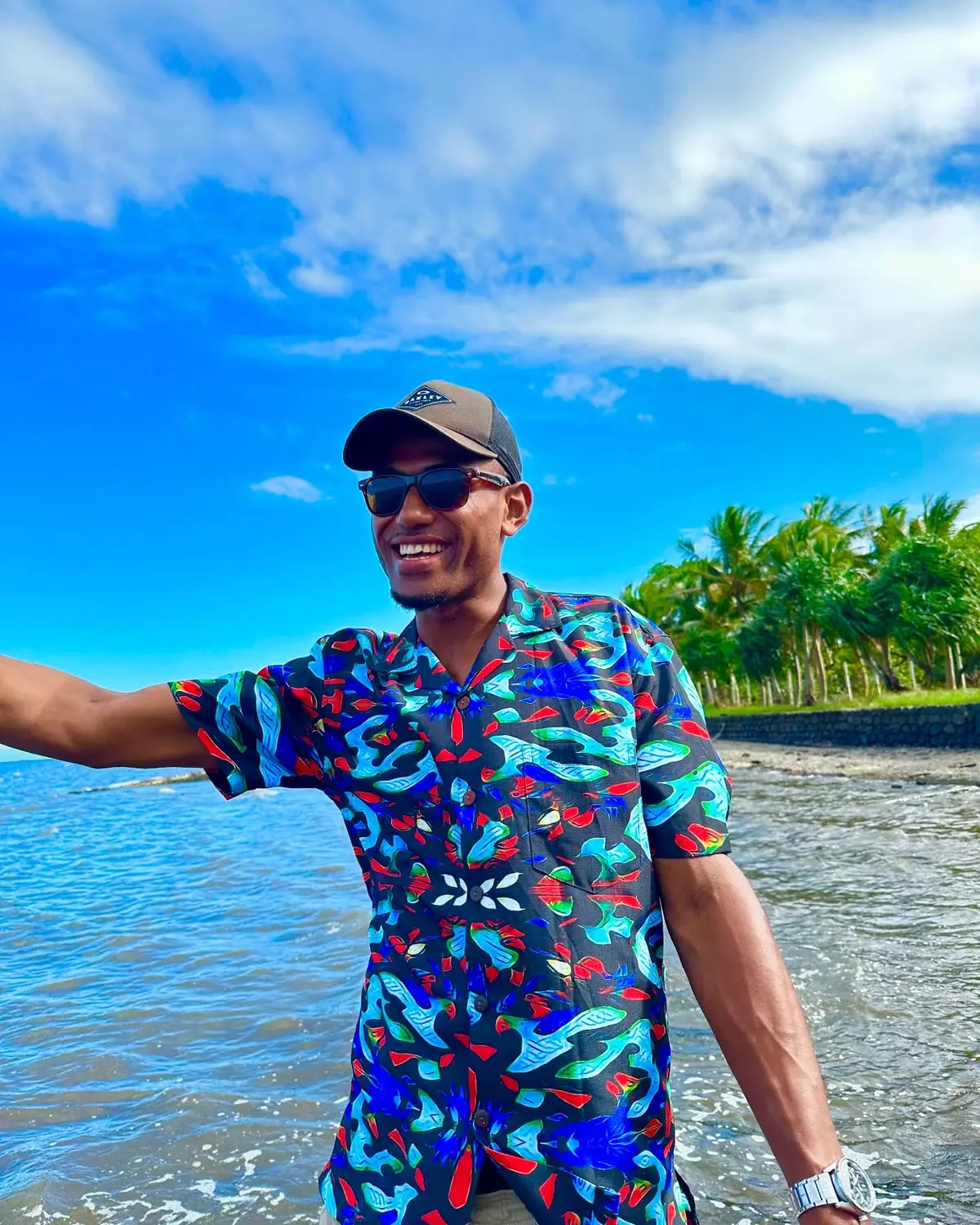 A man wearing a colorful Bula shirt beside the ocean in Fiji